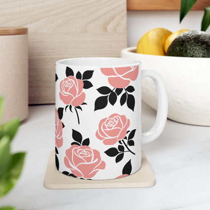 White mug with pink and black floral pattern on a white surface with plants and a bowl in the background